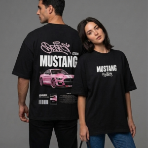 Front and back view of a male and female model styling a black unisex oversized streetwear t-shirt featuring a bold pink Mustang GT500 car graphic, white block lettering, and pink graffiti art on the back.
